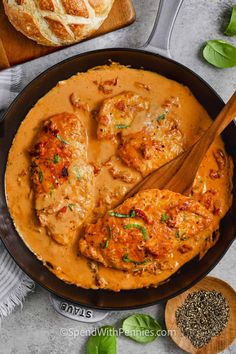 a skillet filled with meat covered in gravy next to bread and vegetables