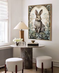 a table with two stools and a painting on the wall