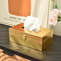 a tissue dispenser sitting on top of a table next to a pink flower