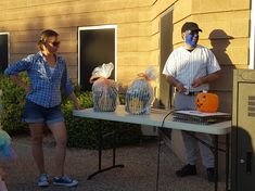 a man and woman standing next to each other in front of a table with plastic bags on it