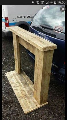 a wooden bench sitting next to a parked car