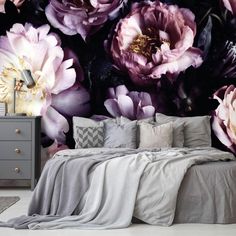 a bed sitting under a large purple flower wall mural