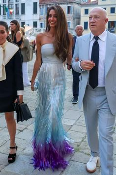 the man and woman are walking down the street together, dressed in formal attire with feathers on them