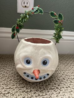 a ceramic owl planter with a green twig in it's mouth and a red nose