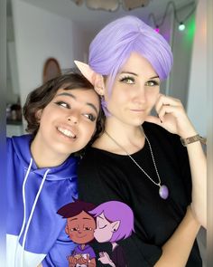 two women with purple hair are posing for the camera