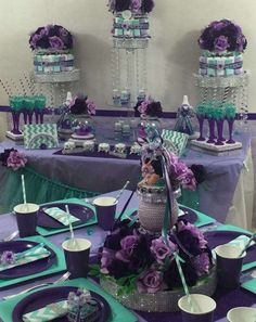 a table with purple and green decorations on it, including plates, cups, napkins and cake