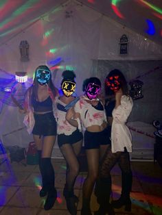 three women in costumes and masks posing for the camera with their faces lit up at night