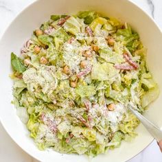 a white bowl filled with lettuce and nuts