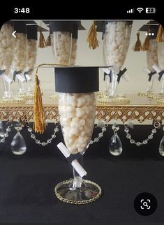 a graduation cap and tassel on top of a wine glass filled with white candy