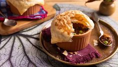 a bowl filled with food sitting on top of a wooden plate next to a spoon