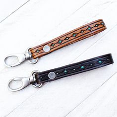 two leather key fobs are sitting on a white table