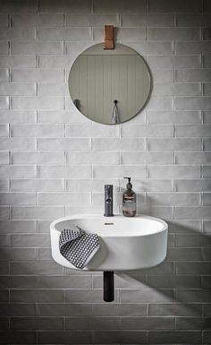 a white sink sitting under a bathroom mirror next to a wall mounted faucet