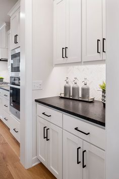 a kitchen with white cabinets and black counter tops