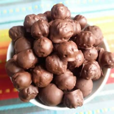 a white bowl filled with chocolate candies on top of a colorful table cloth,