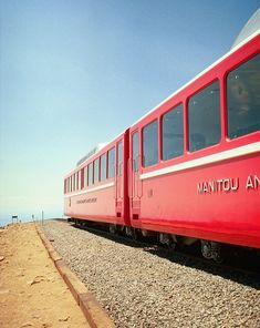 a red train traveling down tracks next to the ocean