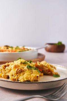 an omelet on a plate with a fork and bowl in the back ground