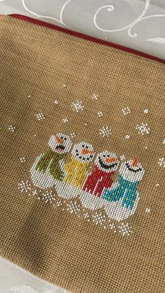 a cross - stitch christmas card with three snowmen on it