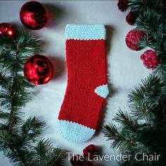 a crocheted christmas stocking laying on top of a table next to ornaments