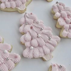 decorated cookies with pink icing and white frosting in the shape of a christmas tree