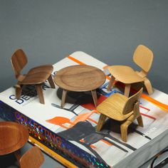 three wooden chairs and one table on top of a book with glasses next to it