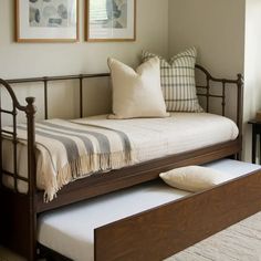 a day bed with a pull out trundle and two framed pictures on the wall