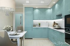 a kitchen with light blue cabinets and white counter tops, along with a dining room table