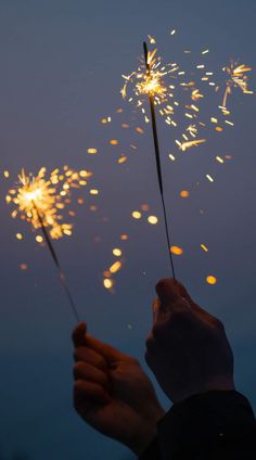 a person holding a sparkler in their hand with the sky in the back ground