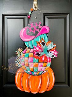 a door hanger decorated with an orange pumpkin and pink cowboy hat