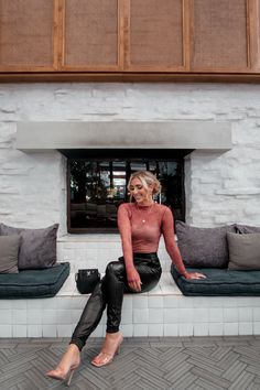 a woman sitting on a bench in front of a window