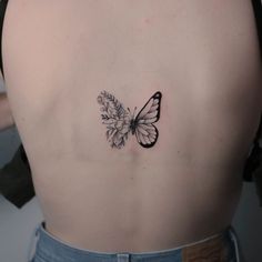 a woman's back with a butterfly and flower tattoo on her left side ribcage