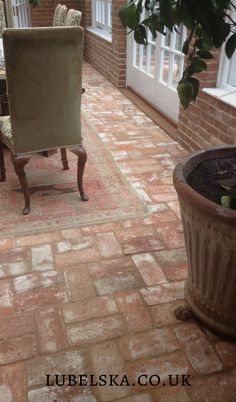 a chair sitting on top of a brick floor next to a potted plant