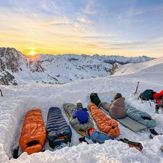 several people laying in the snow with sleeping bags