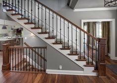 a staircase in a house with wood floors and railings on both sides, leading up to the second floor