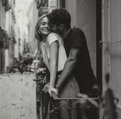 a man and woman embracing each other in an alleyway with buildings on either side