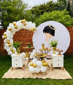 an outdoor party setup with balloons, decorations and tableware on the grass in front of a brick wall