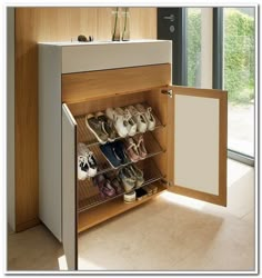 an open cabinet with shoes on it in front of a window