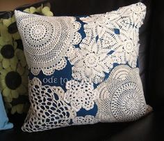 two pillows on a black couch with white crocheted doily and blue fabric