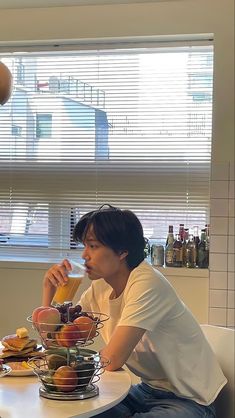 a man sitting at a table with food and drinks in front of him, looking out the window