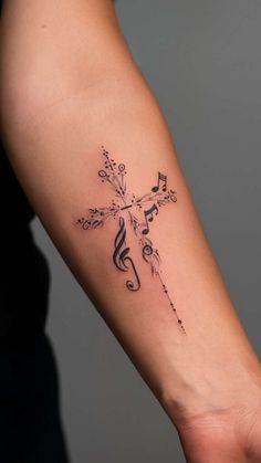 a cross with music notes on it is shown in this tattoo design, which features musical notes