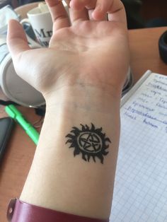 a person's arm with a tattoo on it and a pen in the background