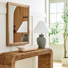 a table with a lamp, mirror and vase on it next to a door way