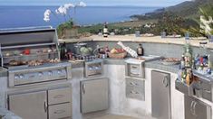 an outdoor kitchen with stainless steel appliances and grills on the outside patio overlooking the ocean