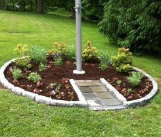 a fire hydrant sitting in the middle of a flower bed on top of a lush green field