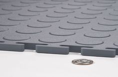 a coin sitting on top of a white table next to some gray plastic squares and circles