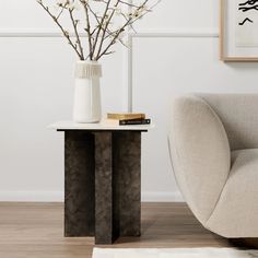 a living room with a chair, table and vase on the floor next to it