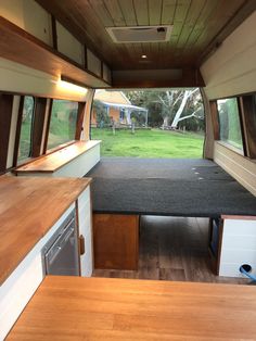 the inside of a camper with wood flooring and white walls, windows, and cabinets