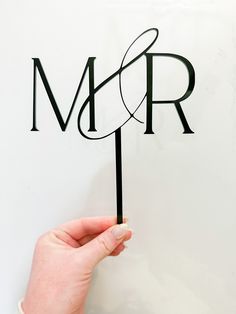 a person holding up a cake topper with the letter m and r on it