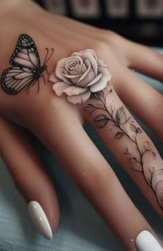 a woman's hand with a rose and butterfly tattoo on it