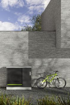 a bike parked next to a building with a green bicycle on the ground near it