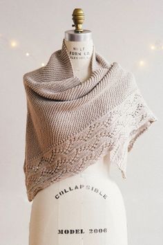 a white mannequin with a knitted shawl on it